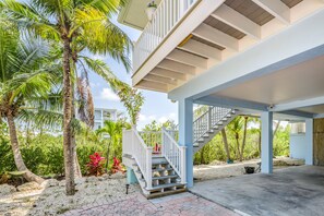 A covered outdoor area with a staircase, palm trees, and a concrete floor. - Amazing waterfront home with private beach, dock, pool, WiFi & outdoor kitchen (Cudjoe Key)
