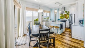 Una cocina moderna con una isla central, armarios blancos y vista al océano.