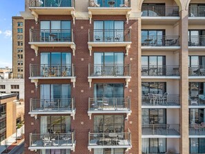 A multi-story residential building with balconies, large windows, and a brick facade. - Pups and Pints - Water View - We Love Dogs (Wilmington)