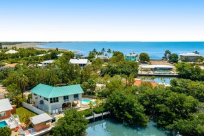 Una proprietà costiera con piscina, un'ampia casa dal tetto verde e vista sul mare.