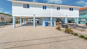 Een gebouw met twee verdiepingen, een overdekte parkeerplaats en een grindpad.