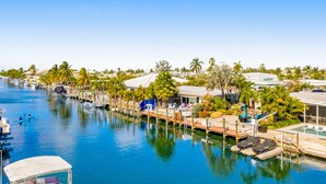 A marina with boats docked, a swimming pool, and palm trees. - Waterfront home with gorgeous patio, WiFi, gas grill, & great location (Key Colony Beach)
