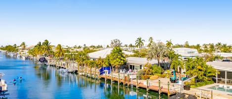 Un puerto deportivo con barcos amarrados, una piscina y palmeras.