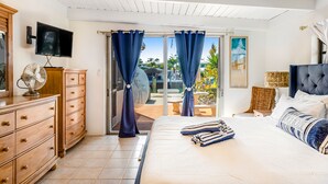 A bedroom with a bed, a dresser, a TV, and a view of the outdoors. - Waterfront home with gorgeous patio, WiFi, gas grill, & great location (Key Colony Beach)