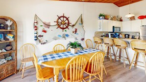 A dining area with a wooden table and chairs, a ceiling fan, and a wall decoration. - Renovated waterfront duplex with canal access, deck, water views & central AC (Marathon)