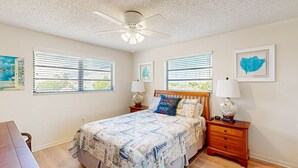 A bedroom with a bed, two bedside tables, a ceiling fan, and two windows with blinds. - Renovated waterfront duplex with canal access, deck, water views & central AC (Marathon)