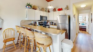 A kitchen with a wooden island, bar stools, a microwave, a refrigerator, and decorative items on the wall. - Renovated waterfront duplex with canal access, deck, water views & central AC (Marathon)