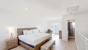 Une chambre avec un lit en bois, des tables de chevet, un banc et une vue sur le balcon.