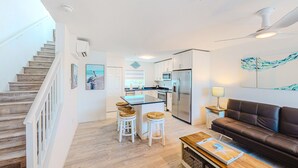 A modern kitchen with a central island, white cabinetry, and a stainless steel refrigerator. - Snowbird-friendly sound view condo with open layout, patio, W/D, & AC (Marathon)