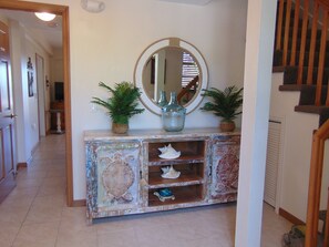 A hallway with a decorative console table featuring a mirror, potted plants, and seashells. - Waterfront home with ocean views, dock, & private outdoor pool (Marathon)