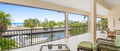 A spacious balcony with a view of the beach and a swimming pool.