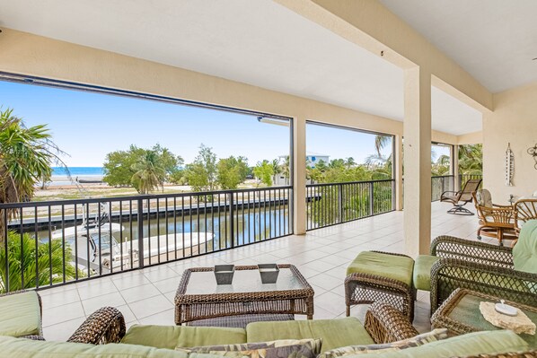 A spacious balcony with a view of the beach and a swimming pool. - Waterfront home with ocean views, dock, & private outdoor pool (Marathon)