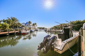 A marina with boats docked, a clear sky, and a house with a blue roof in the background.