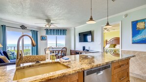 Una cocina con encimeras de granito, lavavajillas y un comedor con mesa y sillas.