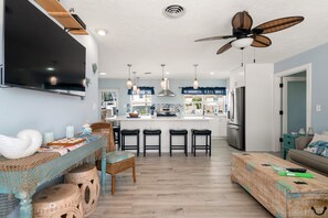A modern kitchen with a central island, bar stools, and a ceiling fan.