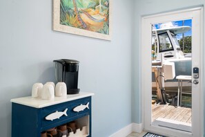 Ein Zimmer mit einer Kaffeemaschine, einem Schrank mit fischförmigen Griffen und einer Tür zu einem Außenbereich mit einem Boot.