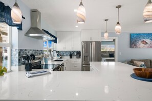 A modern kitchen with white cabinetry, a central island, and pendant lighting.
