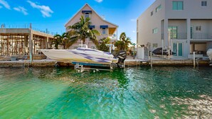 A waterfront property with a boat dock, a building with a balcony, and a clear blue sky. - Modern waterfront home with balcony, patio, grill, W/D, & easy Atlantic access (Marathon)