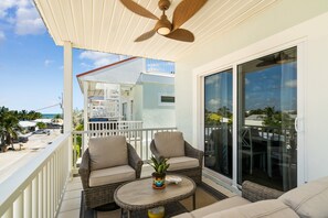 A balcony with wicker furniture, a ceiling fan, and a view of the ocean. - Cozy home with outdoor shared pool, central AC, internet (Marathon)