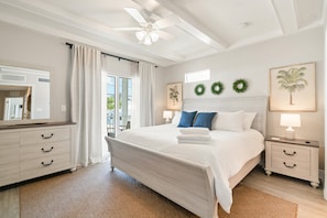 A bedroom with a bed, a nightstand, a dresser, a ceiling fan, and a view of the outdoors. - Cozy home with outdoor shared pool, central AC, internet (Marathon)