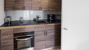 Una cocina moderna con armarios de madera, encimera negra, horno integrado y cafetera.