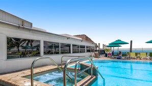 Ein Poolbereich mit Whirlpool, Liegestühlen und Sonnenschirmen.
