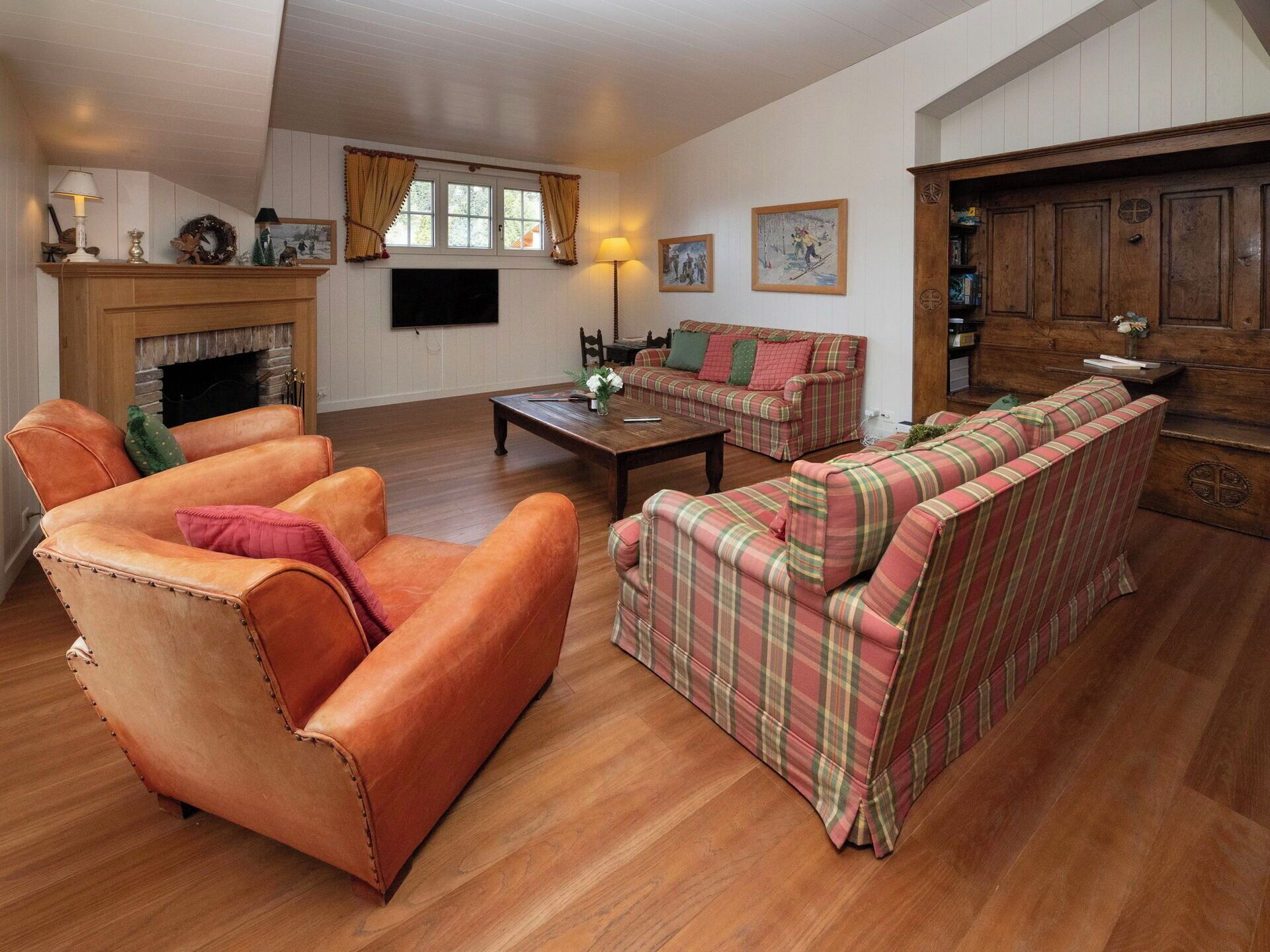 A living room with a fireplace, a television, a sofa set, and a wooden cabinet.