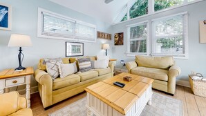 Ein Wohnzimmer mit zwei beigen Sofas, einem Holztisch und einem weißen Beistelltisch mit einer Lampe.