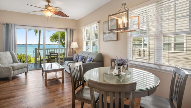 A spacious living area with a balcony overlooking the sea, a round glass table, and a ceiling fan. - Waterfront retreat with balcony views, kayak, SUP, central AC & washer/dryer (Duck Key)