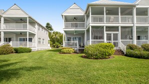 A two-story white house with a balcony on each floor, surrounded by well-maintained lawns and bushes. - Waterfront retreat with balcony views, kayak, SUP, central AC & washer/dryer (Duck Key)