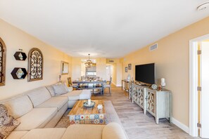 A living room with a sofa, coffee table, TV, and dining area. - Wonderful Condo in Key West w/Free WiFi, Lanai, A/C, Shared Hot Tub & Pool (Key West)