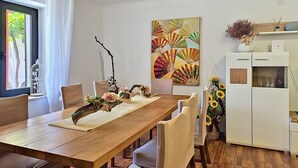 En matplats med ett träbord, vita stolar, en dekorativ bordsdekoration och en stor, abstrakt målning på väggen.