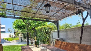 En uteplats med ett träbord, stolar och en pergola.