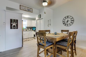 A dining area with a wooden table and chairs, a wall clock, and a kitchen in the background. - Cozy Canal-Front House w/ Free WiFi and Deck - Close to Beaches & State Park (Marathon)