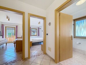 Ein Hotelzimmer mit Bett, einem kleinen Tisch, einem Fenster mit Vorhängen und einem Badezimmer mit Toilette und Waschbecken.