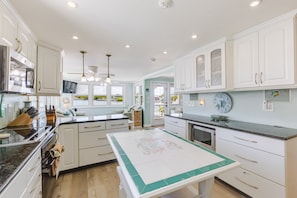 A modern kitchen with white cabinetry, a central island, and a view of the outdoors. - Dog-Friendly Home on the Water w/ Dock, Boat Access, Private Pool, & Free WiFi (Marathon)