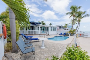 A pool area with lounge chairs, a small pool, and a building with a porch. - Dog-Friendly Home on the Water w/ Dock, Boat Access, Private Pool, & Free WiFi (Marathon)