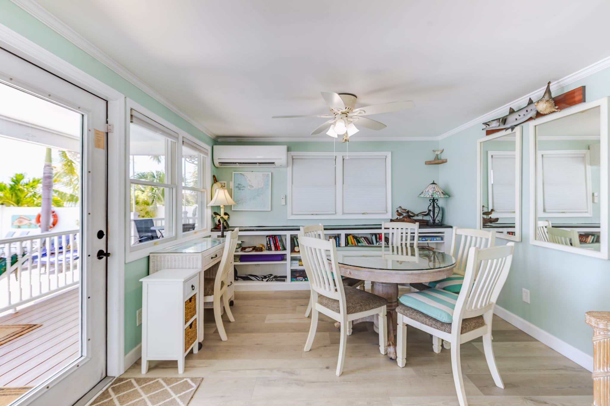 A dining area with a round table, white chairs, and a ceiling fan.