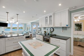 A spacious kitchen with white cabinets, a dining table with a map, and a view of the outdoors. - Dog-Friendly Home on the Water w/ Dock, Boat Access, Private Pool, & Free WiFi (Marathon)