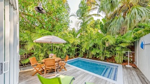 Una terraza de madera con piscina, rodeada de exuberante vegetación tropical.