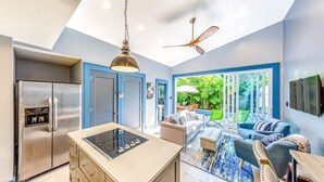 Una cocina moderna con una isla integrada, refrigerador de acero inoxidable y ventiladores de techo.