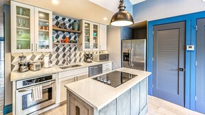 Una cocina moderna con una isla central, electrodomésticos integrados y un salpicadero de diseño geométrico.