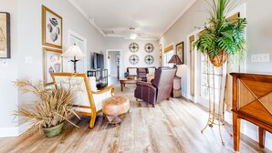 Un salon spacieux avec un plancher en bois, une grande plante et un canapé.