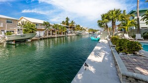 Un port de plaisance avec des bateaux amarrés, une piscine et une rangée de maisons dotées de balcons.