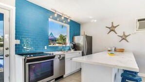 Una cocina con azulejos azules, horno de acero inoxidable, refrigerador y encimera blanca.