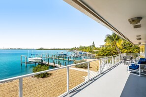 Een balkon met uitzicht op een jachthaven, inclusief boten die aan de steiger liggen en een helderblauwe lucht.