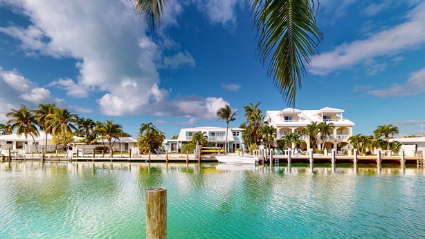 A waterfront property with a pool, palm trees, and a boat dock.