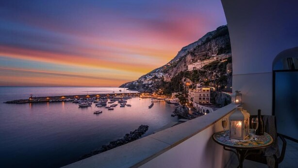 A coastal view with a balcony overlooking a marina, a mountain, and a town. - AMALFI GALLERY (Amalfi)