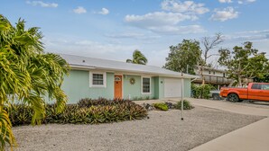 A single-story house with a front door, a small porch, and a driveway. - Waterfront, Single-Story Home on a Canal w/ Dock, Kayaks, AC - 1 Small Dog OK (Key West)