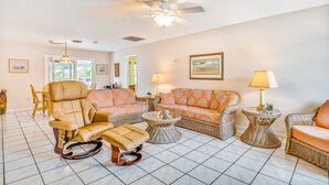 A living room with a ceiling fan, wicker furniture, and a tiled floor. - Waterfront, Single-Story Home on a Canal w/ Dock, Kayaks, AC - 1 Small Dog OK (Key West)